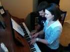 Tess is teaching Trevor how to play the piano duet style.