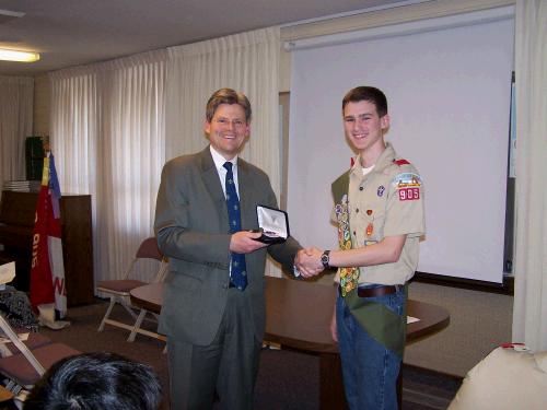 Bishop Valentine (former scoutmaster) awarding Elliot his Eagle Scout award.
